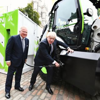 Premiér Boris Johnson tankuje prototyp rýpadla JCB poháněného vodíkem – na počest toho, že společnost JCB oznámila investici 100 milionů liber do výroby vodíkových motorů. Tomu přihlíží předseda JCB Lord Bamford.